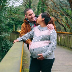 Male looking to pregnant woman holding her belly standing over pathway